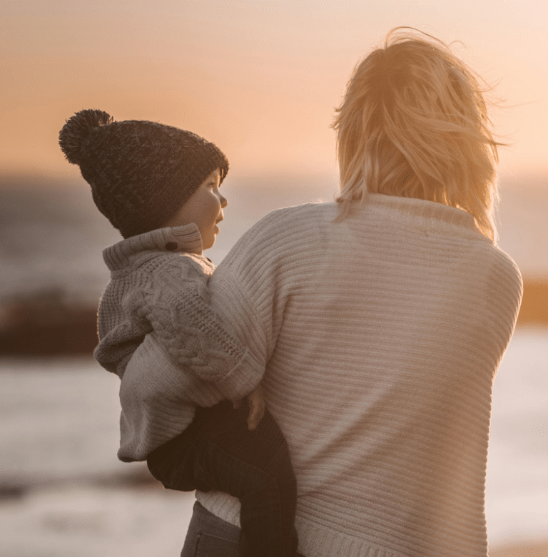mother holding child during sunset